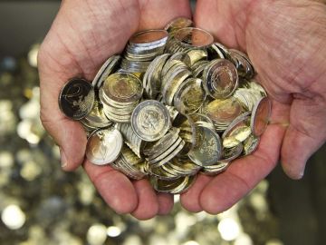 Un hombre sostiene varias monedas de euro Un hombre sostiene varias monedas de euro
