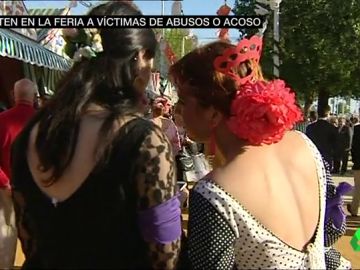 Dos mujeres portan un brazalete morado en la Feria de Abril