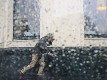 Imagen de archivo de un hombre intentando resguardarse de una tormenta Imagen de archivo de un hombre intentando resguardarse de una tormenta