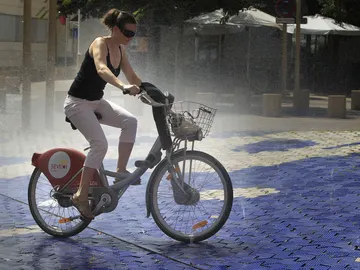 Una joven se refresca en una fuente subida en una bicicleta Una joven se refresca en una fuente subida en una bicicleta