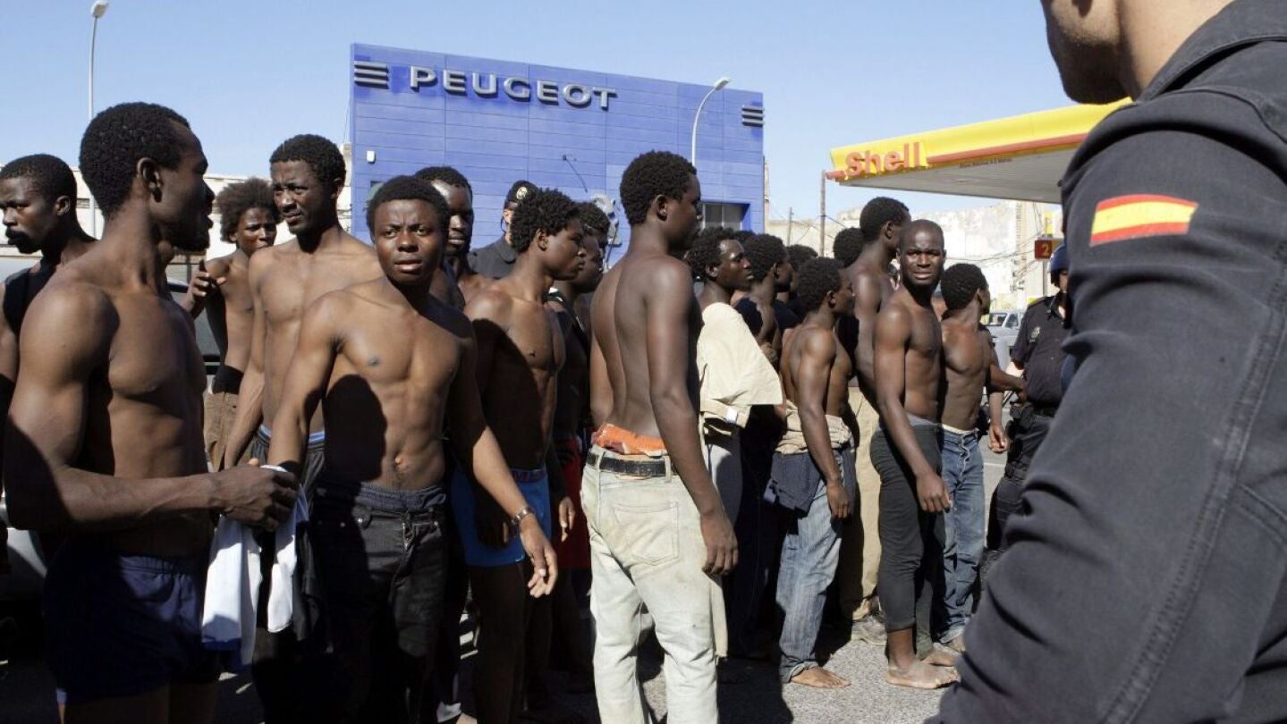Subsaharianos con un polic&iacute;a a la entrada de la Comandancia de la Guardia Civil en Melilla