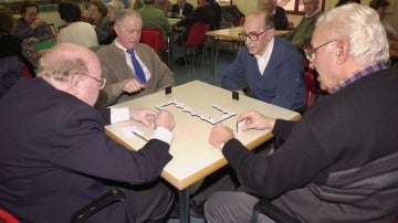 Varios jubilados juegan al dominó