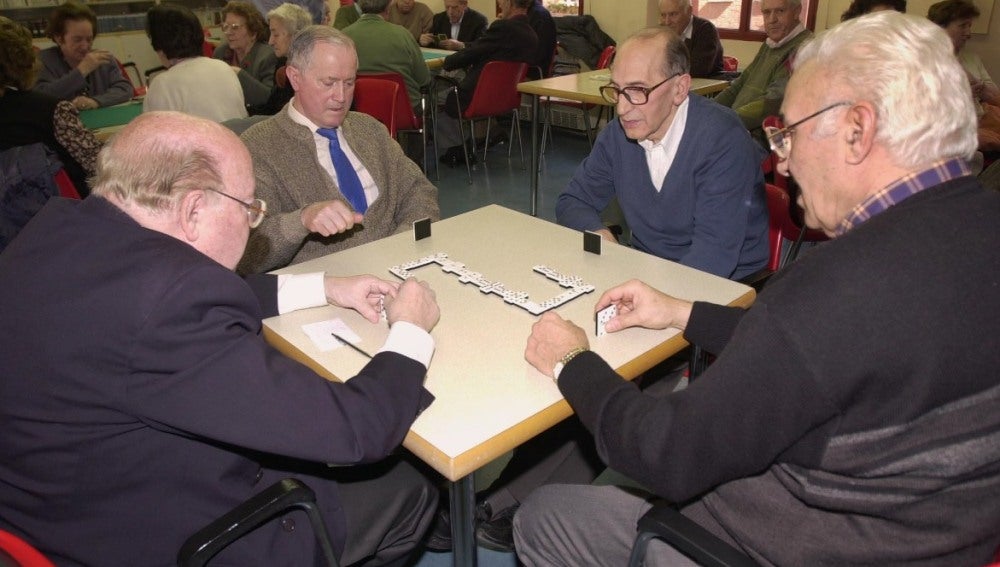 Varios jubilados juegan al dominó