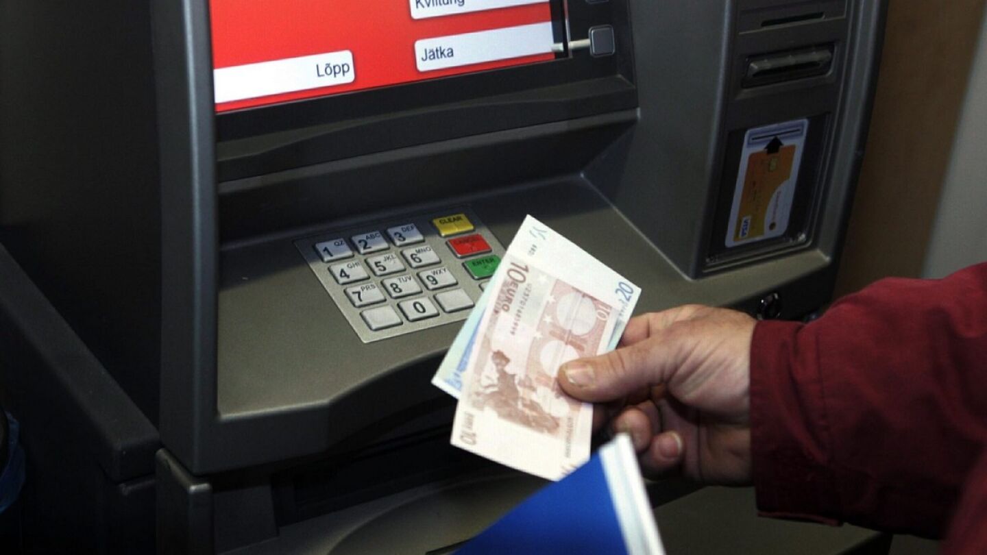 Un hombre retira euros de un cajero autom&aacute;tico. 