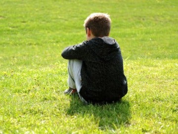 Imagen de archivo de un niño sentado en el césped. Imagen de archivo de un niño sentado en el césped.