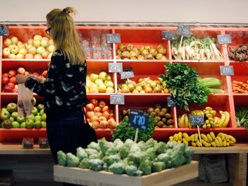 Una mujer hace la compra en la sección de frutas y verduras Una mujer hace la compra en la sección de frutas y verduras