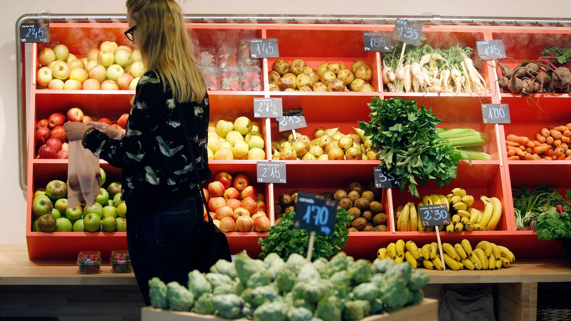 Una mujer hace la compra en la sección de frutas y verduras
