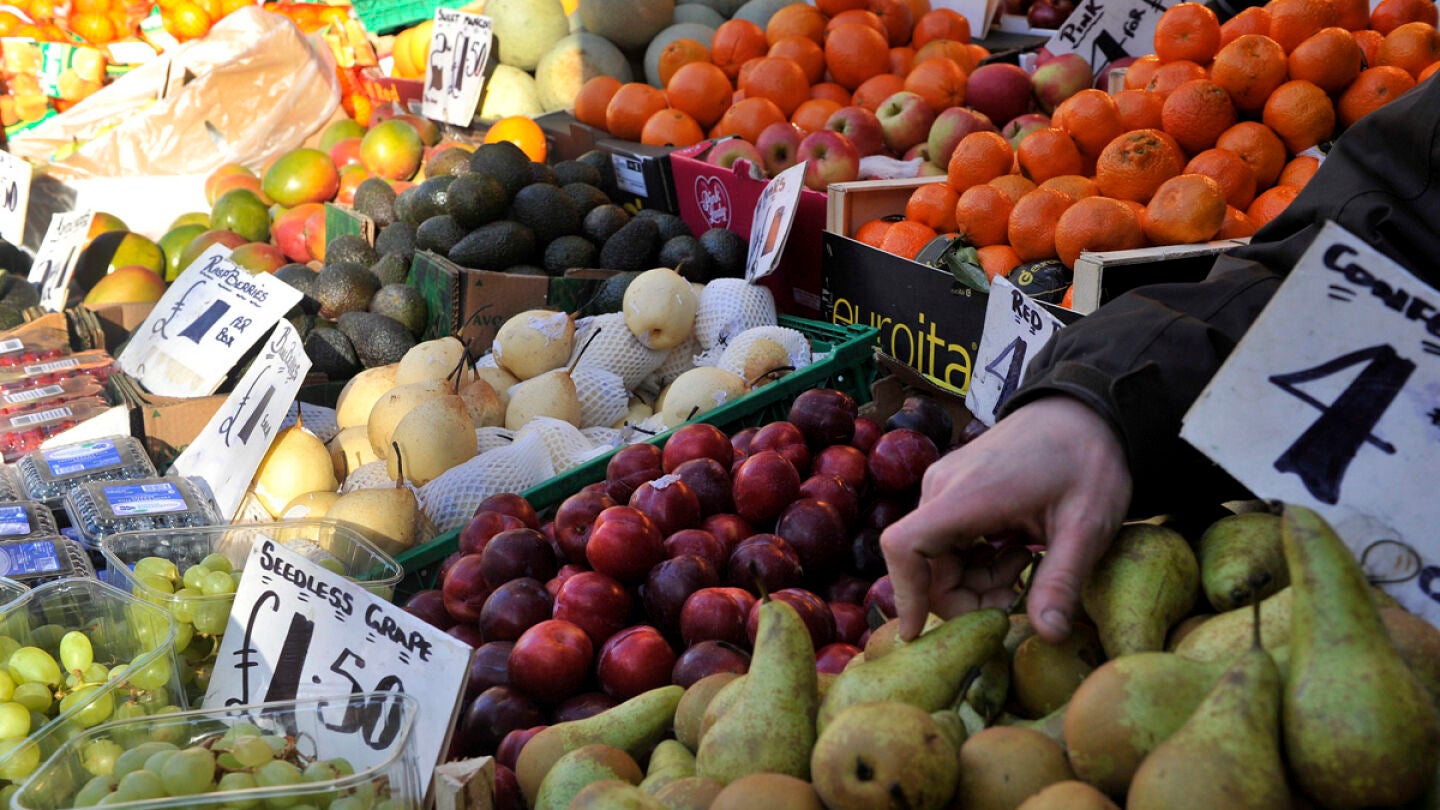 Un vendedor coloca la fruta y verdura en un mercado. 