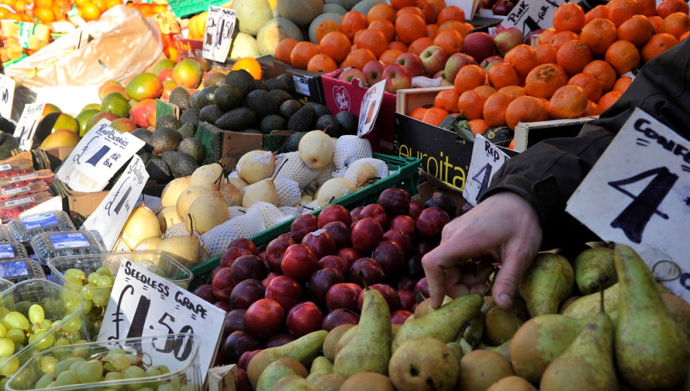 Un vendedor coloca la fruta y verdura en un mercado. 