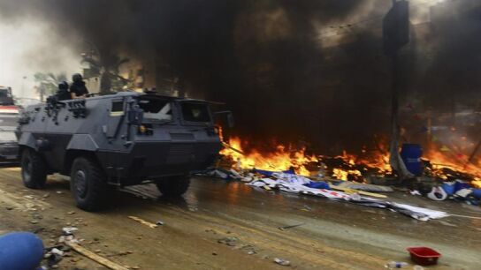 Un tanque pasa al lado de tiendas de campa&ntilde;a incendiadas