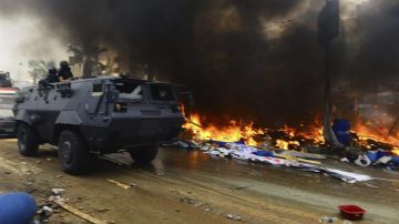 Un tanque pasa al lado de tiendas de campaña incendiadas