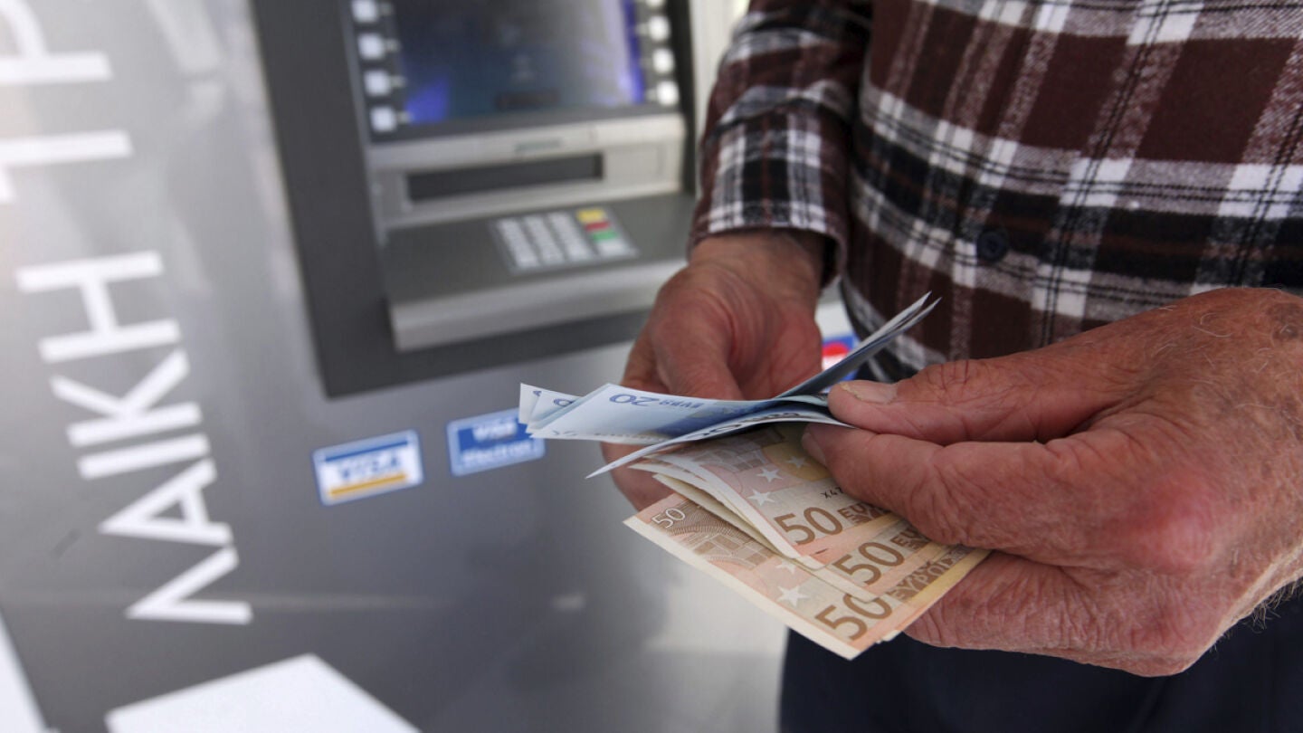 Un hombre saca dinero de un cajero autom&aacute;tico. 