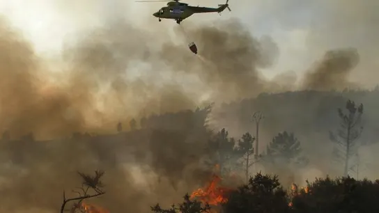 Un helicóptero descarga agua sobre un incendio Un helicóptero descarga agua sobre un incendio