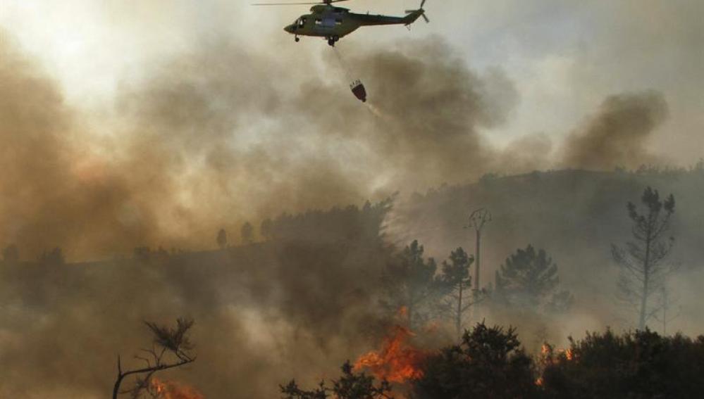 Un helicóptero descarga agua sobre un incendio