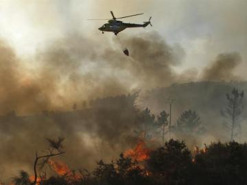 Un helicóptero descarga agua sobre un incendio Un helicóptero descarga agua sobre un incendio