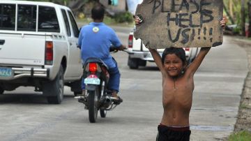 Un niño pide ayuda a los automovilistas en una zona devastada por el paso tifón Haiyan