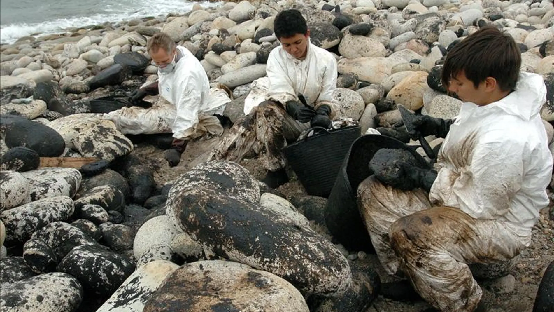 Voluntarios recogen fuel de debajo de las piedras en la costa de Carnota.