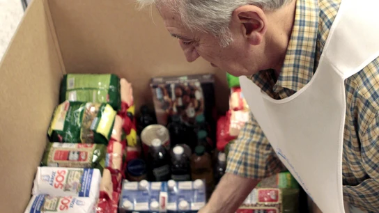 Un voluntario coloca alimentos en una caja Un voluntario coloca alimentos en una caja