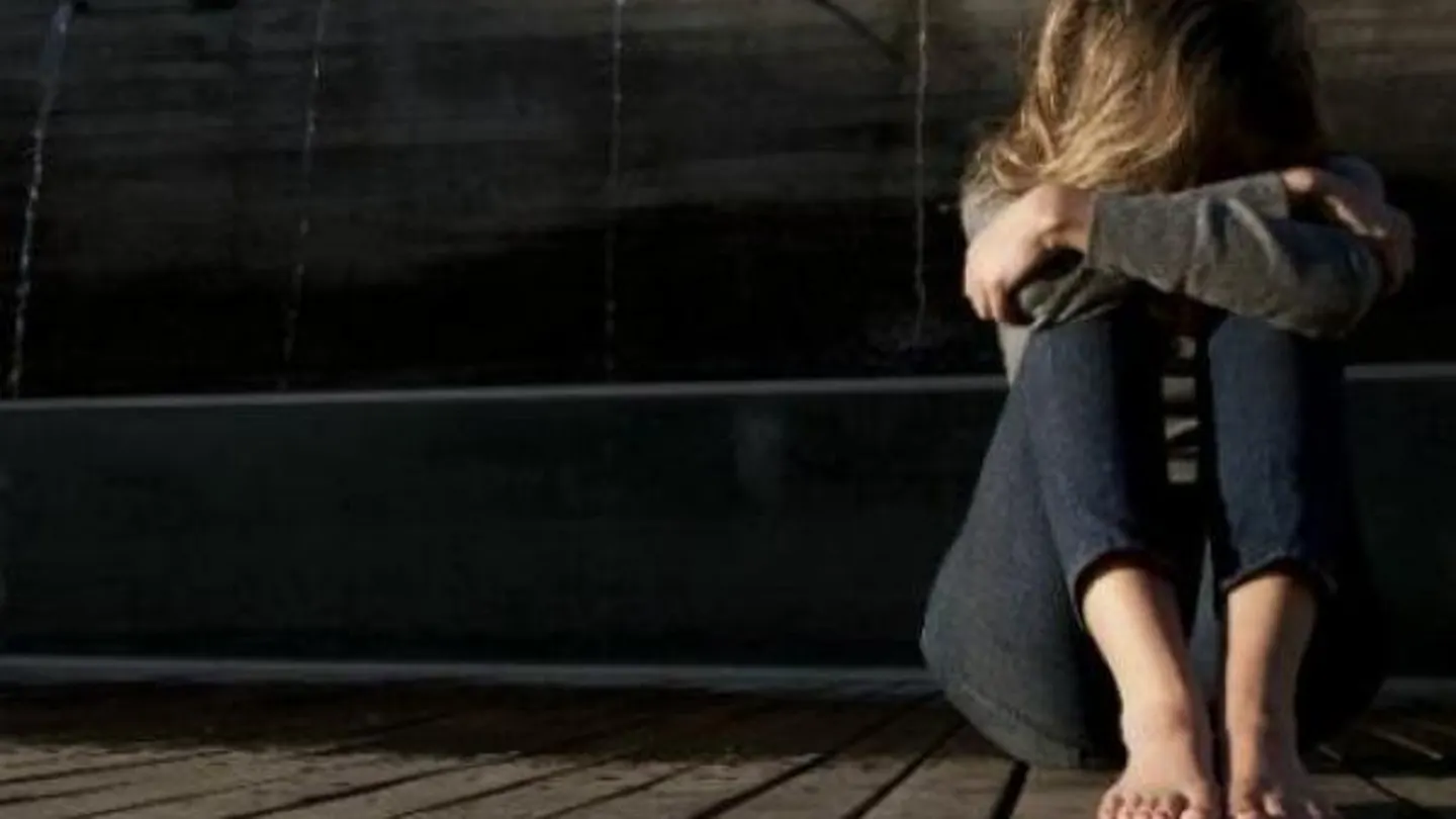 Una menor triste y sentada en el suelo Una menor triste y sentada en el suelo