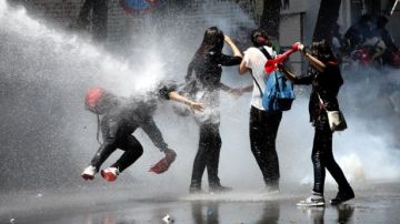 Unos manifestantes son alcanzados por un cañón de agua de la policía antidisturbios