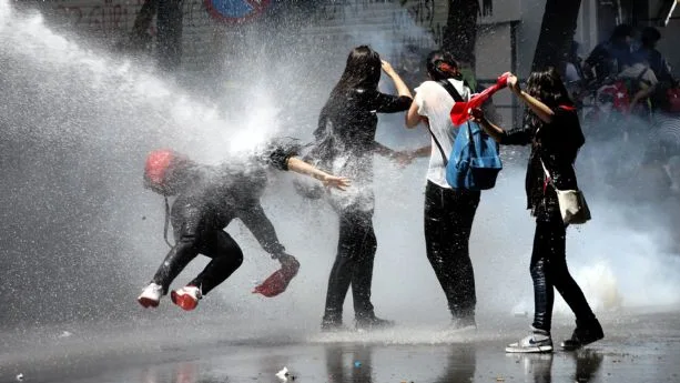 Unos manifestantes son alcanzados por un cañón de agua de la policía antidisturbios