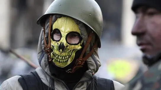 Un manifestante ataviado con un casco militar y con una careta de una calavera Un manifestante ataviado con un casco militar y con una careta de una calavera