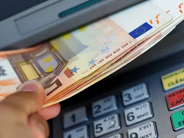 Un usuario recoge efectivo de un cajero automático Un usuario recoge efectivo de un cajero automático