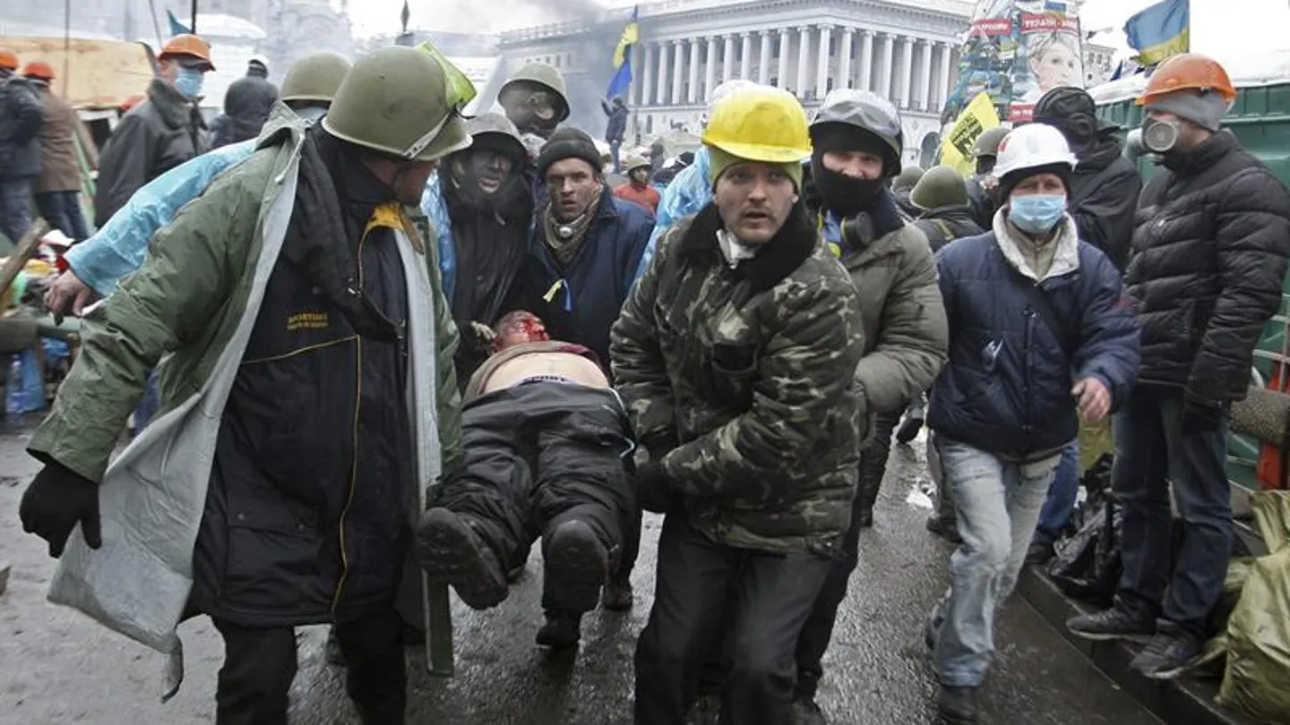 Manifestantes trasladan a un compañero herido durante los enfrentamientos con los antidisturbios en la Plaza de la Independencia Manifestantes trasladan a un compañero herido durante los enfrentamientos con los antidisturbios en la Plaza de la Independencia