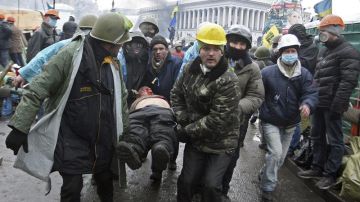 Manifestantes trasladan a un compañero herido durante los enfrentamientos con los antidisturbios en la Plaza de la Independencia