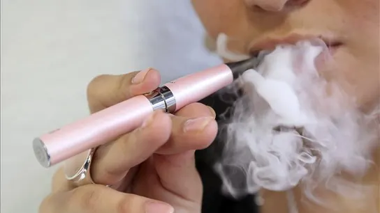 Una mujer fuma un cigarrillo electrónico Una mujer fuma un cigarrillo electrónico