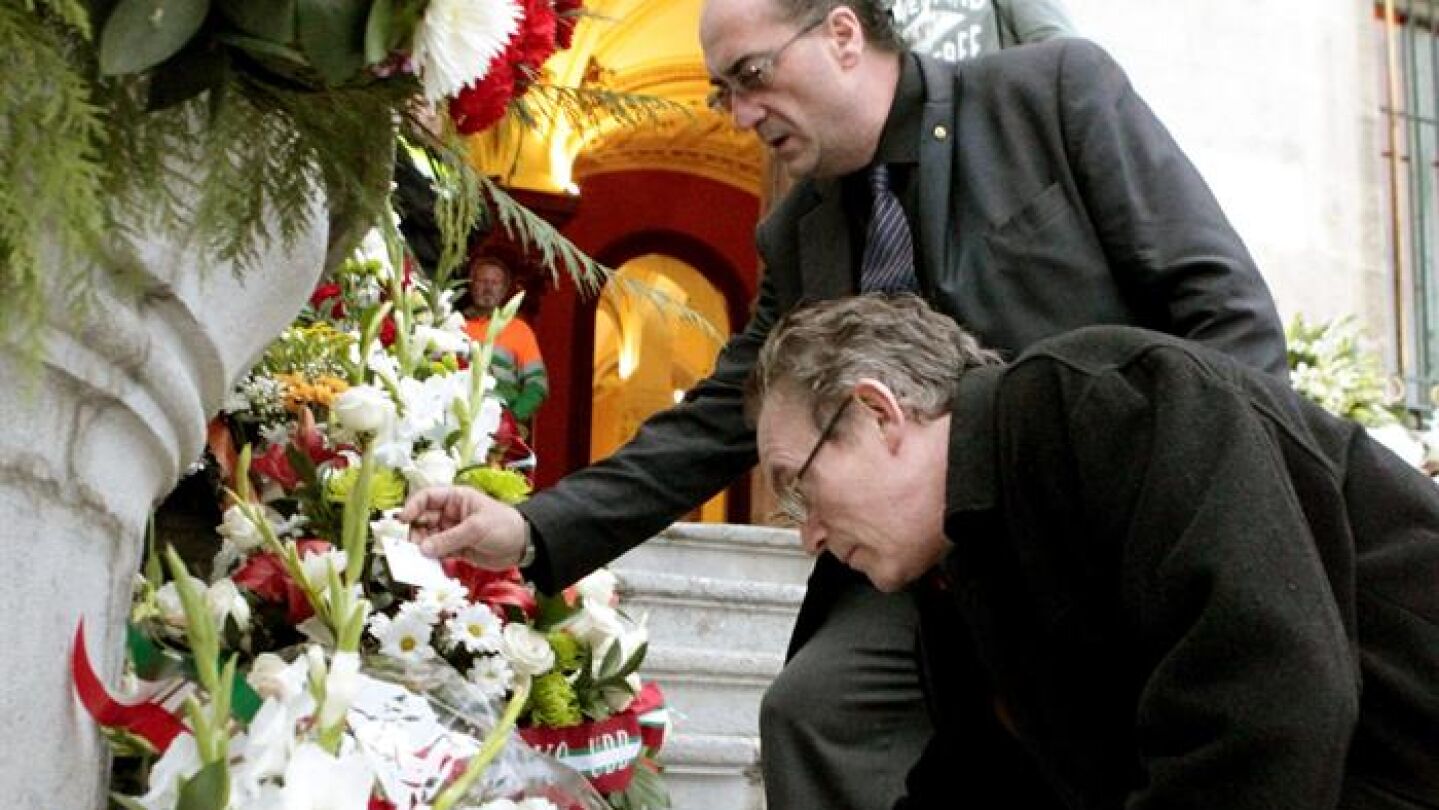 Dos personas depositan flores en la escalinata del Ayuntamiento de Bilbao