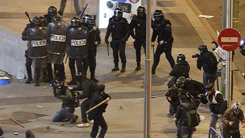  Un joven con un palo ante diversos agentes antidisturbios en las inmediaciones de la Plaza de Colón