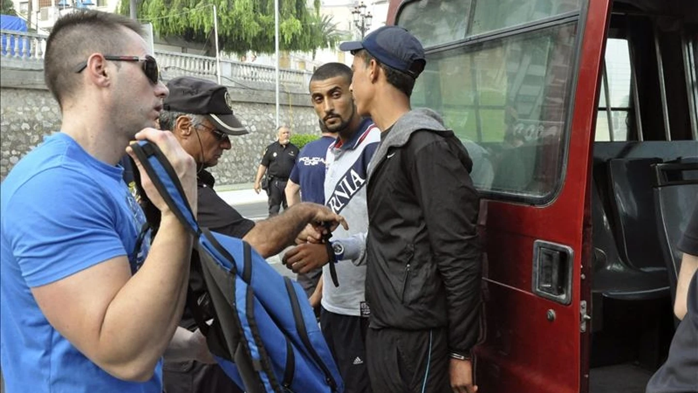 Efectivos policiales junto a varios inmigrantes detenidos Efectivos policiales junto a varios inmigrantes detenidos