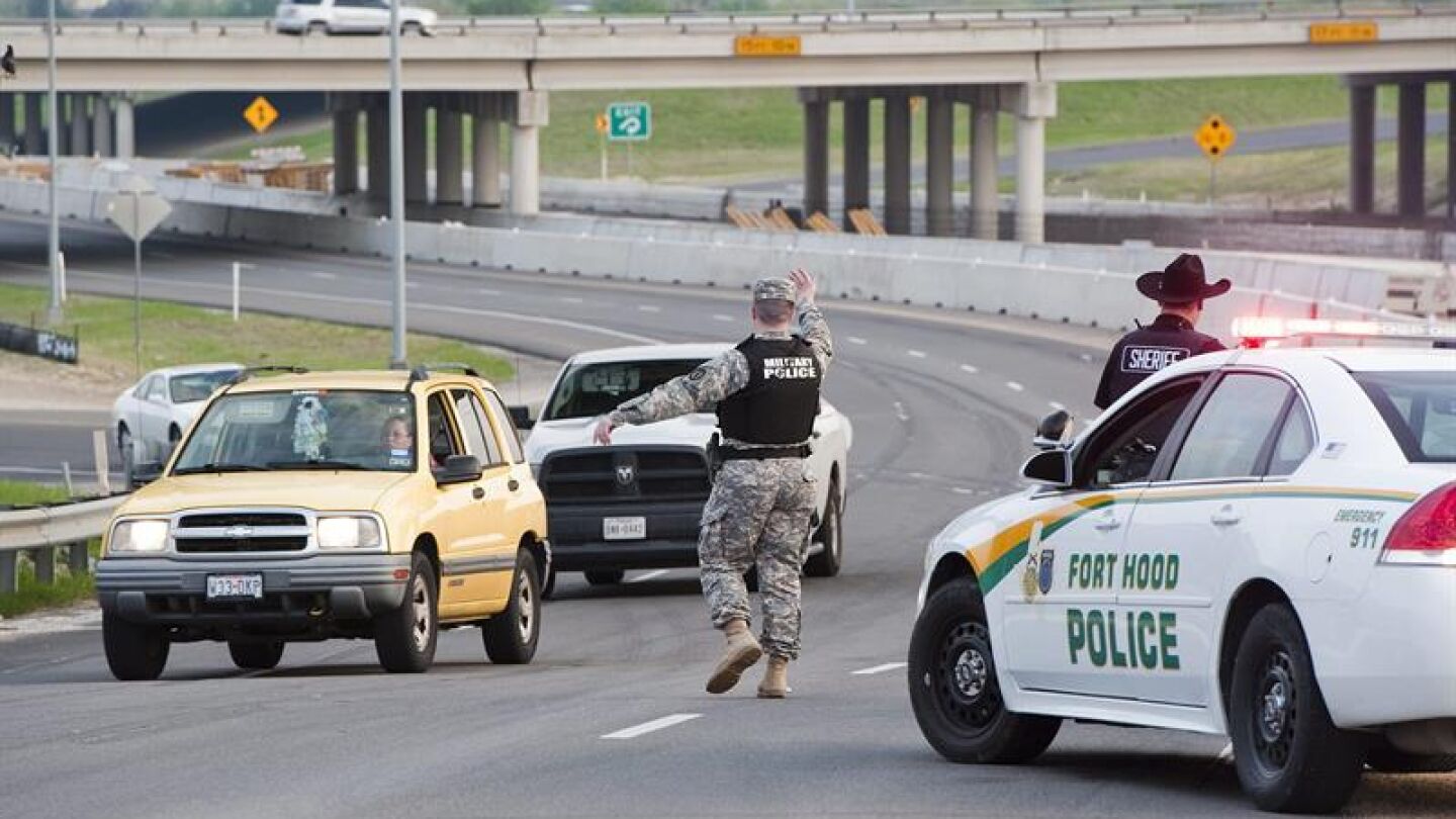 Un polic&iacute;a militar dirige el tr&aacute;fico cerca de la base militar asegurada de Fort Hood