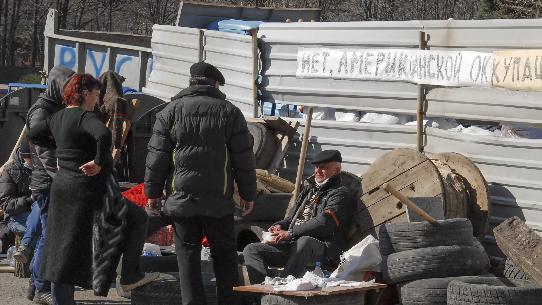 Varios manifestantes prorrusos permanecen sentados junto a una barricada delante del edificio del Servicio de Seguridad, en Lugansk (Ucrania)