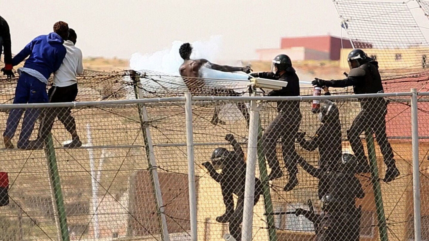 Un polic&iacute;a roc&iacute;a con un extintor a un inmigrante