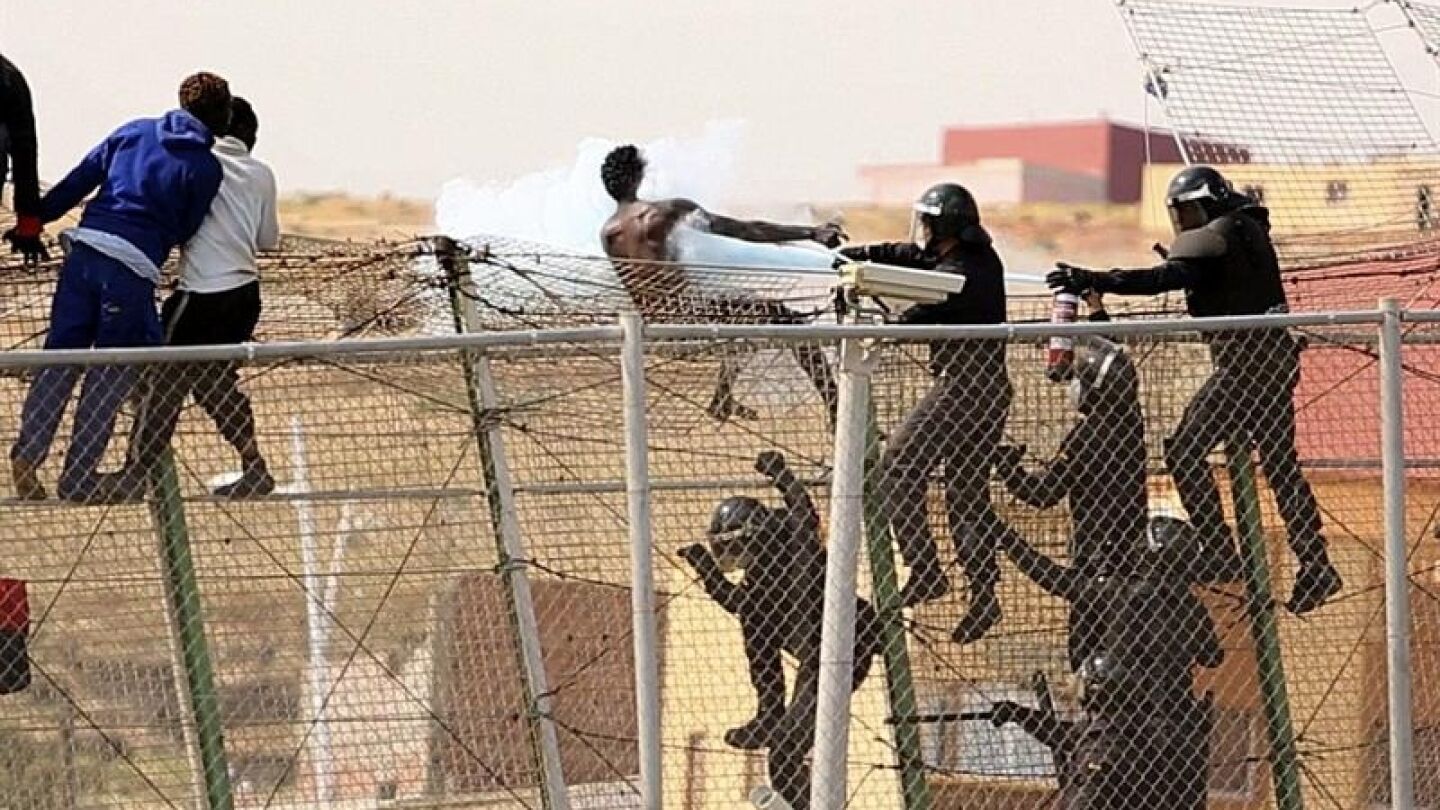 Un polic&iacute;a vac&iacute;a un extintor sobre un inmigrante