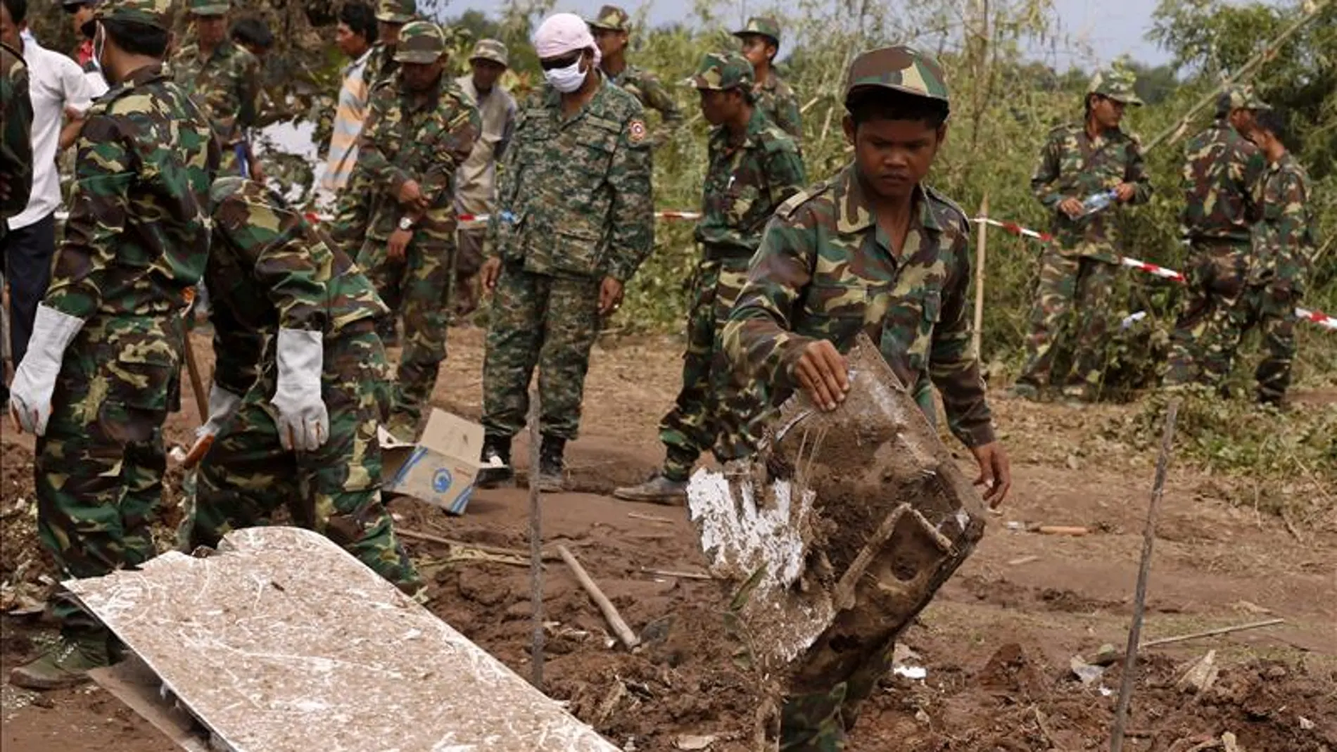 Soldados laosianos recuperan partes del fuselaje de un avión