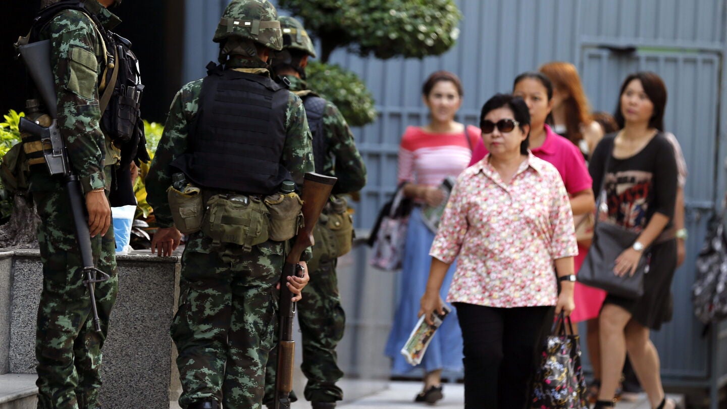Transe&uacute;ntes caminan frente a soldados tailandeses