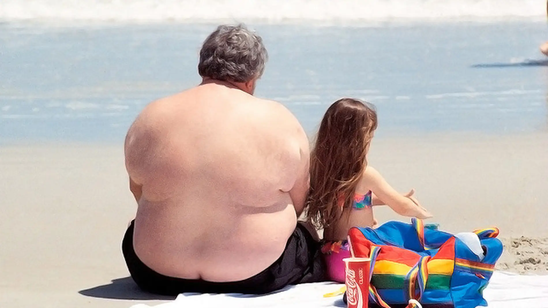 Un hombre obeso descansa en una playa co