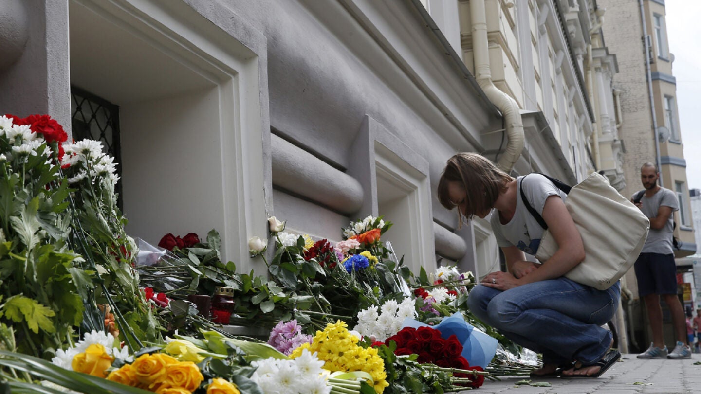 Una mujer deposita flores colocadas a las puertas de la Embajada de Holanda en Mosc&uacute;