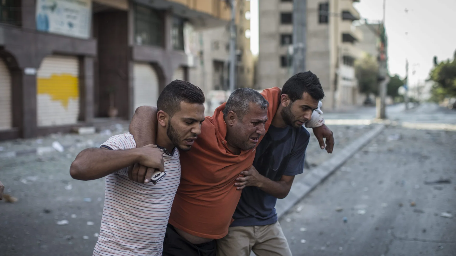 Varios palestinos ayudan a un periodista local que resultó herido en un ataque aéreo israelí 