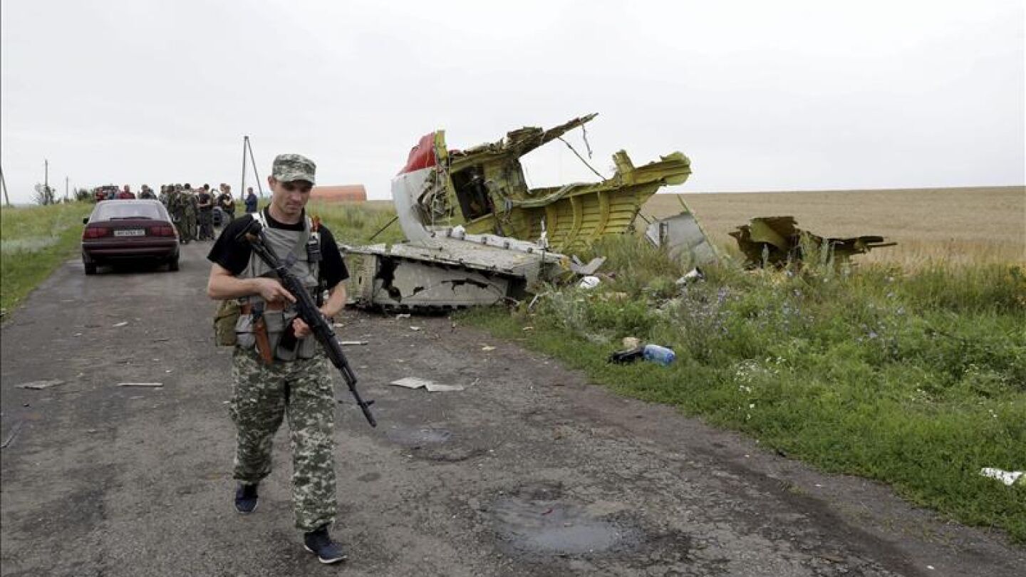 Un rebelde prorruso pasa al lado de restos de fuselaje del avi&oacute;n Boeing 777 del vuelo MH 17