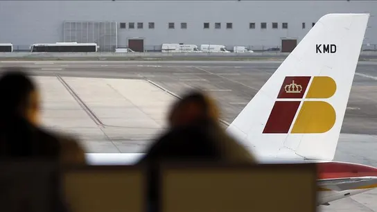 Dos pasajeros contemplan un avión de Iberia Dos pasajeros contemplan un avión de Iberia
