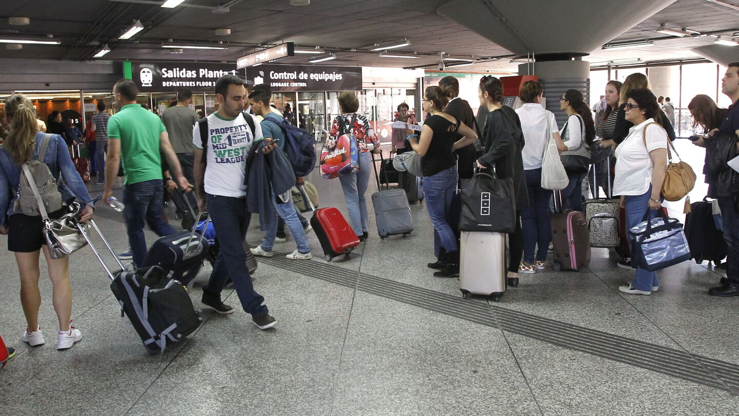 Varios viajeros esperan en la estaci&oacute;n de tren de Atocha, en Madrid