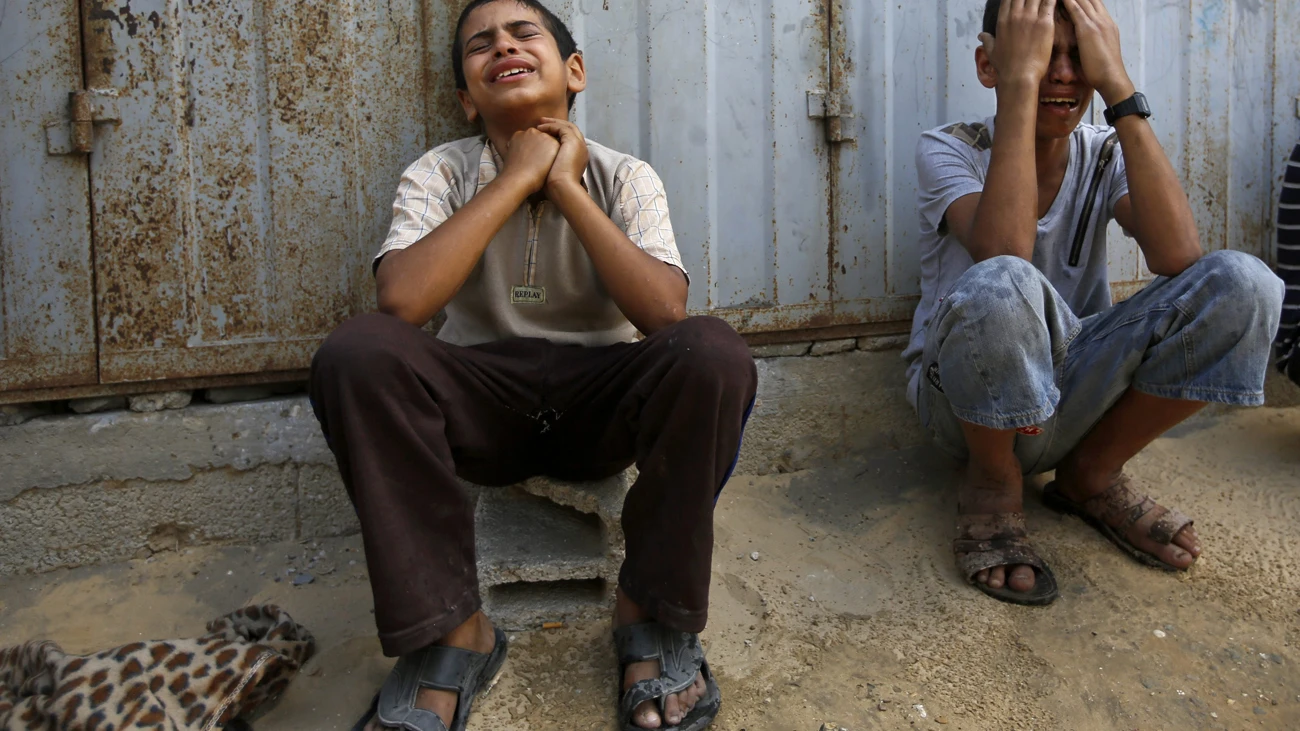 Dos familiares de la familia Shurab lloran junto a los escombros de su casa