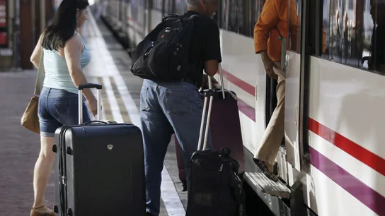 Varias personas montan a un tren en la estación. Varias personas montan a un tren en la estación.
