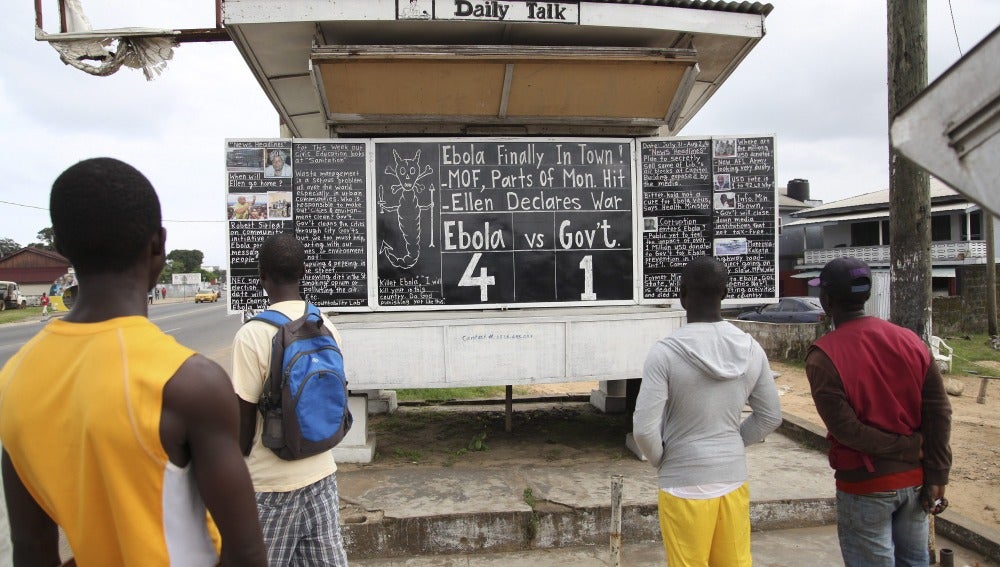Un grupo de personas observa el tablero que anuncia la cifra de víctimas mortales de Ébola 