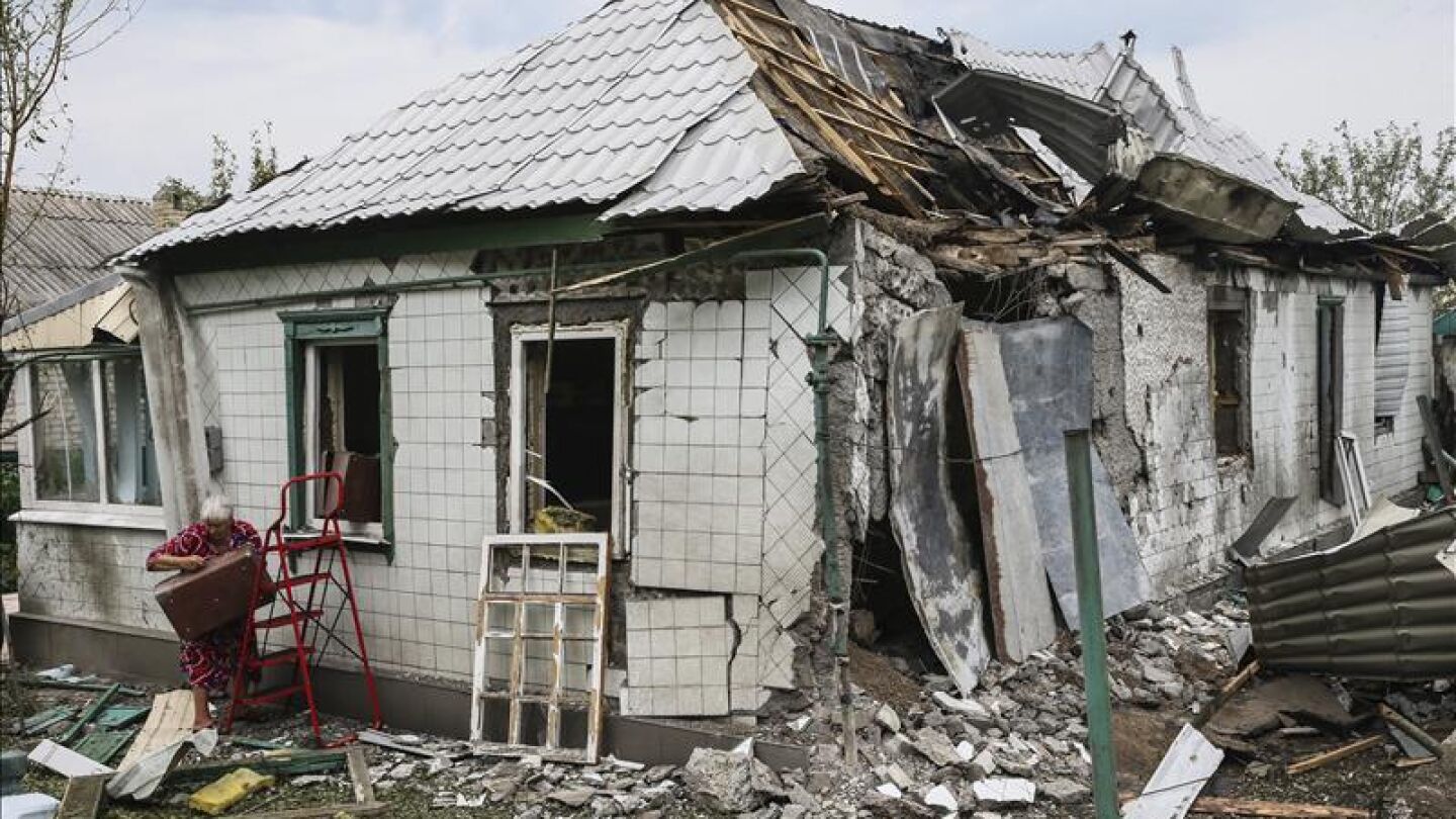 Una mujer recupera sus posesiones del interior de su casa derruida en Khartsyzk