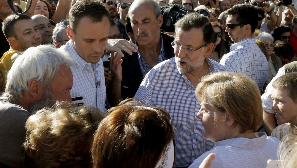 Rajoy y Merkel conversan con varias personas a su llegada a la plaza del Obradoiro